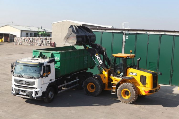 Z lewej strony zielony samochód (hakowiec), z prawej żółta ładowarka